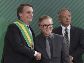 In this Jan. 1, 2019 photo, Brazil's President Jair Bolsonaro, left, shakes hands with Education Minister Ricardo Velez Rodriguez, during a swearing-in ceremony for his cabinet at the Planalto presidential palace, in Brasilia, Brazil. Velez Rodriguez vowed in his inaugural speech to end the "aggressive promotion of the gender ideology."