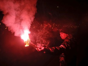 A man holds a flare as people take part in the "Lukov March," staged by the far-right Bulgarian National Union, in Sofia, Bulgaria, Saturday, Feb. 16, 2019. Bulgarian nationalists have marched through Sofia, the country's capital, to honor a World War II general known for his anti-Semitic and pro-Nazi activities. The annual Lukov March, staged by the far-right Bulgarian National Union, attracted hundreds of dark-clad supporters who walked through downtown Sofia holding torches and Bulgarian flags and chanting nationalist slogans.
