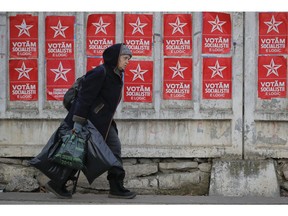 A woman walks by electoral posters advertising the candidates of the Socialists' Party Chisinau, Moldova, Thursday, Feb. 21, 2019, ahead of parliamentary elections taking place on Feb. 24. Moldova's president says the former Soviet republic needs good relations with Russia, amid uncertainty about the future of the European Union.