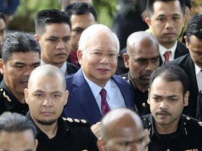 FILE - In this July 4, 2018, file photo, former Malaysian Prime Minister Najib Razak, center, arrives at a court house in Kuala Lumpur, Malaysia. Najib is hardly lying low ahead of his corruption trial set to begin Tuesday, Feb. 12, 2019, on charges related to the multibillion-dollar looting of the 1MDB state investment fund. He's crooned about slander in an R&B video and vilified the current government on social media to counter portrayals of him as corrupt and out of touch. Najib denies wrongdoing and his lawyers are seeking delay.