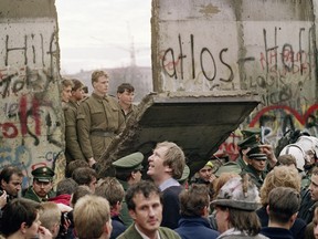 West Berliners crowd in front of the Berlin Wall on Nov. 11, 1989 as they watch East German border guards demolishing a section of the wall in order to open a new crossing point between East and West Berlin, near the Potsdamer Square.