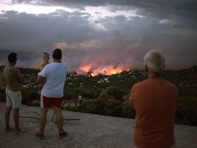 People watch a wildfire in the town of Rafina, near Athens, on July 23, 2018.