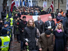 Veterans of the Latvian Legion, a force that was commanded by the German Nazi Waffen-SS during the Second World War, and their sympathizers carry flags and posters as they walk to the Monument of Freedom in Riga, Latvia on March 16, 2019 to commemorate a key 1944 battle in their ultimately failed attempt to stem a Soviet advance.