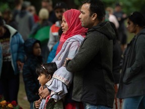 A Muslim family stands by the mosque where worshipers were gunned down in Christchurch.