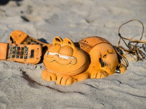 Spare parts of plastic Garfield phones are displayed on the beach on March 28, 2019 in Plouarzel, western France, after being collected from a sea cave by environmental activists. For more than 30 years, plastic phones in the shape of the famous cat have been washing up on French beaches. The mystery is now solved: a shipping container which washed up during a storm in the 1980s was found in a hidden sea cave.