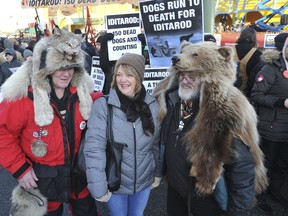 Anchorage residents, from left, Waino Salo, Lorene Grant and Richard Zeigler pose in front a People for the Ethical Treatment of Animals protest prior to the ceremonial start of the Iditarod Trail Sled Dog Race Saturday, March 2, 2019 in Anchorage, Alaska.