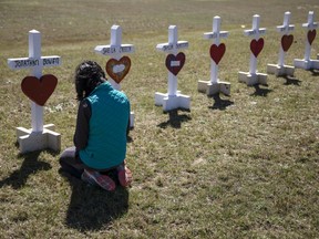 Jessica Taylor prays in front of a cross for Jonathan Bowen, 9, at a makeshift memorial for the victims of a tornado in Beauregard, Ala., Wednesday, March 6, 2019. "I have a son his age," said Taylor. "I can't imagine that mother's loss."
