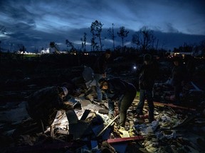 Family and friends of David Wayne Dean, who died when a tornado destroyed his house, sift through the rubble by flashlight at dusk to help his wife look for personal mementos in Beauregard, Ala., Monday, March 4, 2019.