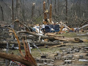 Brittney Downs looks through the debris of a family member's destroyed home the day after a deadly tornado ravaged the area, in Beauregard, Ala., Monday, March 4, 2019.