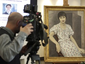 A cameraman films a painting, "Portrait of Kiki", falsely attributed to 20th century painter Moise Kisling, during a press conference announcing the conclusion of the preliminary phase of an investigation of 21 paintings seized by Carabinieri during an exhibition in 2017, in central Rome, Wednesday, March 13, 2019.