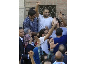 FILE - In this Aug. 28, 2014 file photo, surrounded by plainclothes policemen, Egyptian prominent blogger Alaa Abdel-Fattah waves to the crowd after attending the funeral of his father, Ahmed Seif, in Cairo, Egypt. A leading Egyptian pro-democracy activist was released from prison early Friday March 29, 2019, after serving a five-year sentence for inciting and taking part in protests, his family and lawyer said.