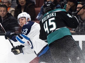 Winnipeg Jets left wing Brandon Tanev, left, gets hit by Anaheim Ducks defenseman Andy Welinski during the first period of an NHL hockey game in Anaheim, Calif., Wednesday, March 20, 2019.