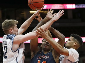 Cal State Fullerton guard Khalil Ahmad, center, and UC Irvine forward Tommy Rutherford, left, and guard Evan Leonard, right, vie for the ball during the first half of an NCAA college basketball game for the Big West men's tournament championship in Anaheim, Calif., Saturday, March 16, 2019.