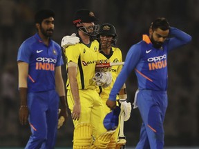 India's captain Virat Kohli, right, reacts as Australia's Ashton Turner and Jhye Richardson smile while walking back to the pavilion after winning the fourth one day international cricket match against India in Mohali, India, Sunday, March 10, 2019.