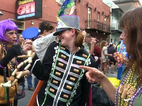 In this Friday, Feb. 22, 2019, image made from video, a woman wearing a marching band costume taunts revelers with trinkets and beads in the Krewe of Cork parade in New Orleans. New Orleans now boasts some 50 walking Carnival clubs that parade throughout the Mardi Gras season. That's the most ever in the city's long Carnival history, making Mardi Gras more colorful and diverse than ever before.