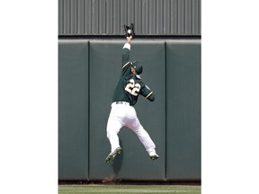 Oakland Athletics center fielder Ramon Laureano leaps at the wall to snag a deep fly ball from Chicago Cubs' Anthony Rizzo to end the top of the first inning of a spring training baseball game Wednesday, March 13, 2019, in Mesa, Ariz.