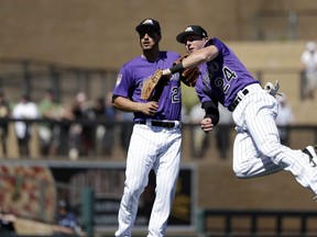Colorado Rockies second baseman Ryan McMahon (24) throws to first as third baseman Nolan Arenado looks on after McMahon fielded a ground ball from Cincinnati Reds' Jesse Winker in the third inning of a spring training baseball game Monday, March 18, 2019, in Scottsdale, Ariz. Winker was out on the play.