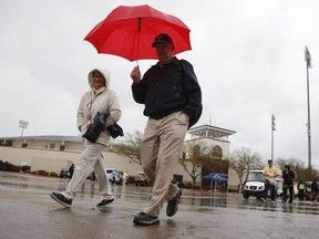 Stadium staff walk back to their cars as they leave Surprise Stadium after a spring training baseball game between the Kansas City Royals and the Chicago White Sox was called off due to rain Tuesday, March 12, 2019, in Surprise, Ariz.