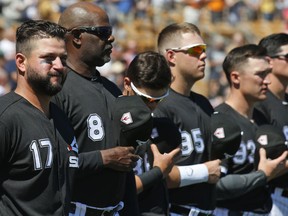 Chicago White Sox first baseman Yonder Alonso (17), first base coach Daryl Boston (8) and other team members stand for the national anthem before a spring training baseball game against the San Francisco Giants, Monday, March 18, 2019, in Glendale, Ariz.