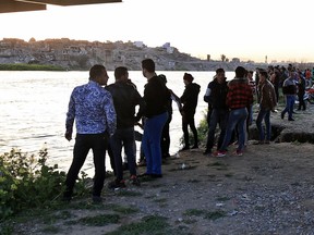 People and relatives of victims waiting on the bank of the Tigris river where the ferry sank in Mosul, Iraq, Thursday, March 21, 2019. A ferry overloaded with people celebrating the Kurdish new year sank in the Tigris River near the Iraqi city of Mosul on Thursday, killing dozens of people, mostly women and children, officials said.