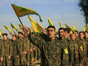 FILE - In this Feb. 13, 2016 file photo, Hezbollah fighters hold flags as they attend the memorial of their slain leader Sheik Abbas al-Mousawi, who was killed by an Israeli airstrike in 1992, in Tefahta village, south Lebanon. U.S. Secretary of State Mike Pompeo's visit to Lebanon this week is expected to underscore the Trump administration's displeasure with Hezbollah's growing influence in Lebanese politics. The Iranian-backed group wields more power than ever in the country's Cabinet and parliament.