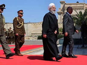 Iranian President Hassan Rouhani, center, walks with Iraqi President Barham Salih, before their meeting at Salam Palace in Baghdad, Iraq, Monday, March 11, 2019. Rouhani is visiting Iraq, seeking to boost ties between the two neighboring states and possibly secure Iraq's help in bypassing U.S. sanctions the Trump administration re-imposed last year.