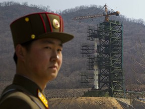 FILE - In this April 8, 2012, file photo, a soldier stands in front of the Unha-3 rocket at a launching site in Tongchang-ri, North Korea. North Korea is reportedly restoring facilities at its long-range rocket launch site that it had dismantled as part of disarmament steps last year. A major South Korean newspaper reports that the country's spy service gave such an assessment to lawmakers in a private briefing on Tuesday.