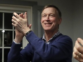 FILE - In this Feb. 13, 2019, file photo, former Colorado Gov. John Hickenlooper, left, applauds at a campaign house party,  in Manchester, N.H. Hickenlooper is running for president, becoming the second governor to jump into the sprawling Democratic 2020 contest. Hickenlooper is a former brewpub owner and Denver mayor who hopes his two terms governing a swing state shows that he can unite the country.