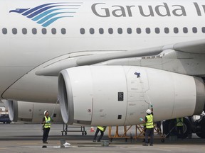 FILE - In this Sept. 28, 2015, file photo, workers clean a jetliner at GMF AeroAsia facility at Soekarno-Hatta International Airport in Jakarta, Indonesia. Indonesia's flag carrier is seeking the cancellation of a multibillion-dollar order for 49 Boeing 737 Max 8 jets, citing a loss of confidence in the model following two crashes in the space of a few months.