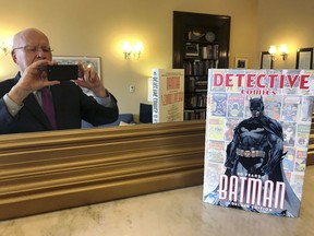 This Thursday, March 28, 2019, photo provided by Sen. Patrick Leahy, D-Vt., shows Leahy in a mirror and the 80th anniversary edition of a book commemorating the superhero Batman. Leahy, who wrote the forward for the book, has been a Batman fan since first reading the comic books as a child growing up in the 1940s in Montpelier, Vt. Leahy also has made brief appearances in a number of Batman movies.