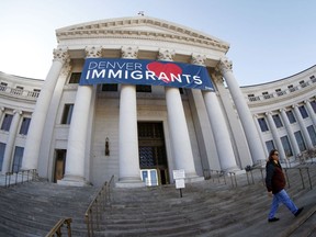 FILE - In this Feb. 26, 2018 file photo, a banner to welcome immigrants is shown through a fisheye lens over the main entrance to the Denver City and County Building. The U.S. Justice Department told The Associated Press at the end of February 2019 that 28 jurisdictions, including Denver, that were targeted in 2017 over what it considered "sanctuary" policies have been cleared for law enforcement grant funding.