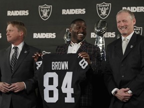 Oakland Raiders wide receiver Antonio Brown, center, holds his jersey beside coach Jon Gruden, left, and general manager Mike Mayock during an NFL football news conference Wednesday, March 13, 2019, in Alameda, Calif.