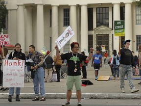 Oakland Technical High School teacher Cris Bautista, center, gestures to motorists as he pickets in front of the school, Friday, March 1, 2019, in Oakland, Calif. Bautista teaches high school in Oakland, but to afford to live in the San Francisco Bay Area, he commutes an hour or more to an apartment he shares with another teacher and works weekends at a coffee shop. Bautista is among Oakland educators who are currently out on strike to push for a 12 percent pay raise, arguing their salaries are not nearly keeping up with the soaring cost of living in a region flush with technology industry money.