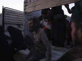 People climb off of a truck after being evacuated out of the last territory held by Islamic State militants, outside Baghouz, Syria, Monday, March 4, 2019. Hundreds of people including IS fighters evacuated their last foothold in eastern Syria hours after U.S.-backed Syrian fighters said they were forced to slow their advance because the extremists are using civilians as human shields.