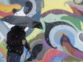 Rain drops are shown on a window as a man walks past a mural in San Francisco, Wednesday, March 6, 2019. Drenching rain is causing roadway flooding and traffic accidents as another storm pounds California.