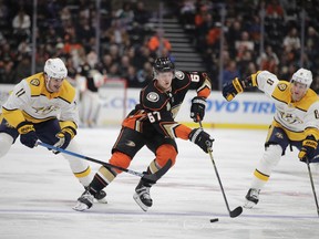 Anaheim Ducks' Rickard Rakell, center, of Sweden, moves the puck past Nashville Predators' Brian Boyle, left, and Kyle Turris during the second period of an NHL hockey game, Tuesday, March 12, 2019, in Anaheim, Calif.