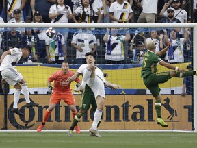 Los Angeles Galaxy's Joe Corona, left, heads the ball next to teammate Zlatan Ibrahimovic and Portland Timbers defender Bill Tuiloma, right, during the first half of an MLS soccer match Sunday, March 31, 2019, in Carson, Calif.