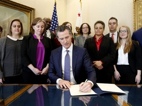 Gov. Gavin Newsom signs the executive order placing a moratorium on the death penalty at his Capitol office Wednesday, March 13, 2019, in Sacramento, Calif.