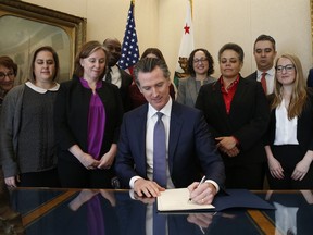 Gov. Gavin Newsom signs the executive order placing a moratorium on the death penalty at his Capitol office Wednesday, March 13, 2019, in Sacramento, Calif.