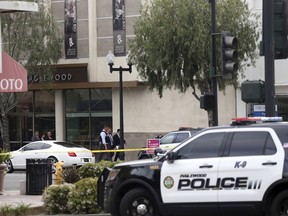 Investigators leave the Church of Scientology, at left rear, after a shooting in Inglewood, Calif., Wednesday, March 27, 2019. Two police officers and a suspect were shot Wednesday after law enforcement responded to reports of a man with a sword entering the Church of Scientology in Inglewood, authorities said.