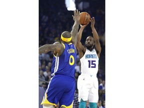 Charlotte Hornets guard Kemba Walker (15) takes a 3-point shot over Golden State Warriors center DeMarcus Cousins (0) during the first half of an NBA basketball game Sunday, March 31, 2019, in Oakland, Calif.