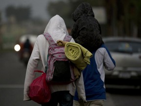 Honduran migrants carry their belongings on their backs as they walk at dawn along the roadside through Esquipulas, Guatemala, as they make their way toward the U.S. border on Wed. Jan. 16, 2019.