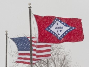 FILE - In this Feb. 1, 2011 file photo, an American and Arkansas flag blow in the wind as snow falls in Fayetteville, Ark.  An Arkansas House panel on Wednesday, March 20, 2019 rejected for a second time a proposal to change the meaning of a star on the state's flag that currently represents the Confederacy, despite an endorsement from the Republican governor.