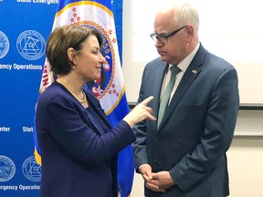 FILE - In this March 15, 2019 file photo, Minnesota Gov. Tim Walz, right, and Sen. Amy Klobuchar, D-Minn., talk before a briefing from state and federal emergency managers who are gearing up for a flood threat caused by some of the heaviest snow in years in St. Paul, Minn. Democratic presidential candidate Klobuchar is proposing an infrastructure plan she says will provide $1 trillion to fix roads and bridges, protect against flooding and rebuild schools and other projects. The plan announced Thursday is the first policy proposal from the Minnesota senator since she joined the 2020 race.