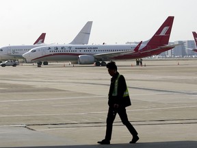 A ground crew walks near a Boeing 737 Max 8 plane operated by Shanghai Airlines parked on the tarmac at Hongqiao airport in Shanghai, China, Tuesday, March 12, 2019. U.S. aviation experts on Tuesday joined the investigation into the crash of an Ethiopian Airlines jetliner that killed 157 people, as a growing number of airlines grounded the new Boeing plane involved in the crash. (AP Photo)
