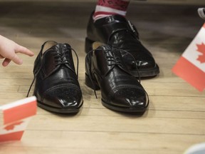 A child points to the new budget shoes being put on by Federal Finance Minister Bill Morneau in a pre-budget photo opportunity in Toronto on Thursday, March 14, 2019. Morneau visited the Toronto and Kiwanis Boys and Girls Club for the media event.