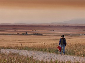 A resident of the Blood Reserve, southeast of Waterton Lakes National Park, Alta. walks down a side road near Standoff, Alberta, in heavy smoke Tuesday, September 12, 2017. Members of a southern Alberta First Nation have voted overwhelmingly to accept a $150 million claim settlement from the federal government. The Blood Tribe filed a claim nearly two decades ago alleging Canada mismanaged their once lucrative cattle business in the early 1900s.