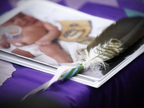 An eagle feather and a baby hospital ID bracelet sit on a photo of a newborn baby during a press conference in support of the mother who's newborn baby was seized from hospital by Manitoba's Child and Family Services (CFS) at First Nations Family Advocate Office in Winnipeg on Friday, January 11, 2019. A newborn who was seen in a social media video being taken away from her mother by authorities in a Winnipeg hospital is returning to her family.