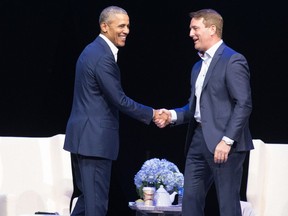 Former U.S. President Barack Obama and Michael Burns, CEO of the Princess Margaret Cancer Foundation, shake hands at the Bell MTS Centre, in Winnipeg in a Monday, March 4, 2019, handout photo. Obama says there is a danger in the United States and around the world with politics being driven by passions disconnected from facts.