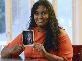 In this July 17, 2018, photo, Tamara Lanier holds an 1850 photograph of Renty, a South Carolina slave who Lanier said is her family's patriarch, at her home in Norwich, Conn. The portrait was commissioned by Harvard biologist Louis Agassiz, whose ideas were used to support the enslavement of Africans in the United States. Lanier filed a lawsuit on Wednesday, March 20, 2019 in Massachusetts state court, demanding that Harvard turn over the photo and pay damages.